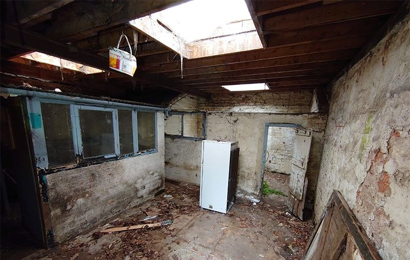 Rear room with collapsed roof, exposed joists and stripped brickwork before refurbishment