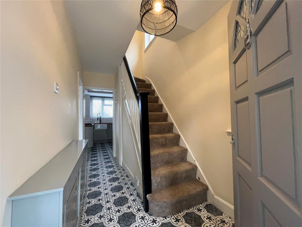 Completed entrance hall with patterned tiled floor, black balustrade and pendant lighting