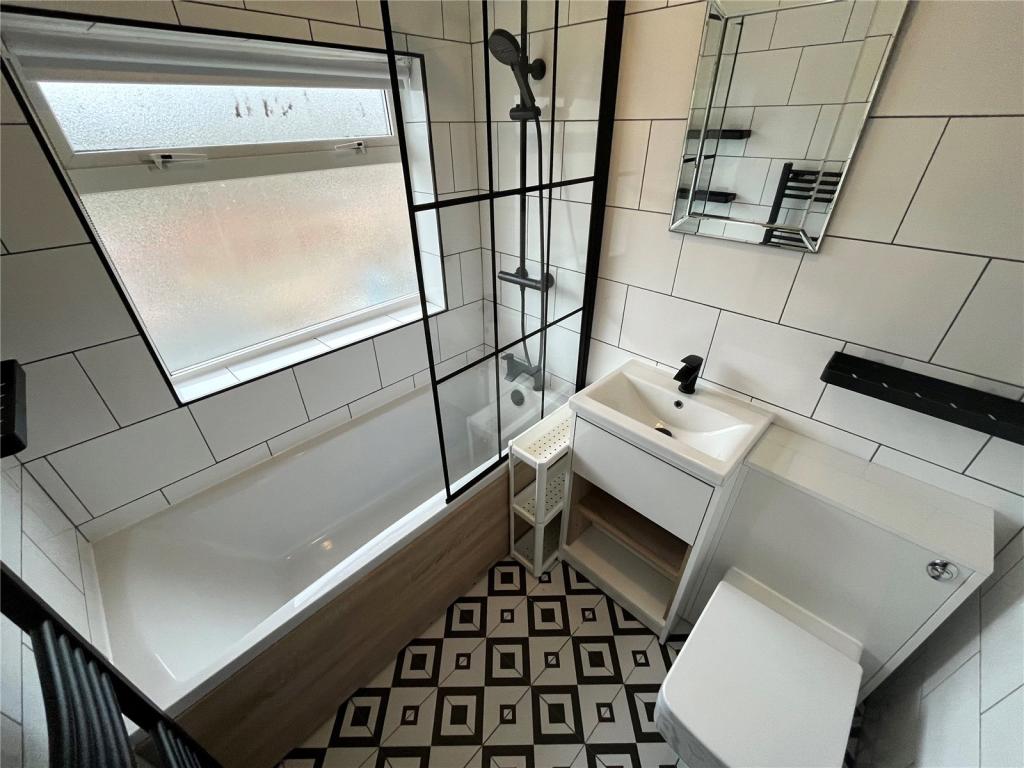 Completed bathroom with white metro tiling, black framed shower screen and vanity unit
