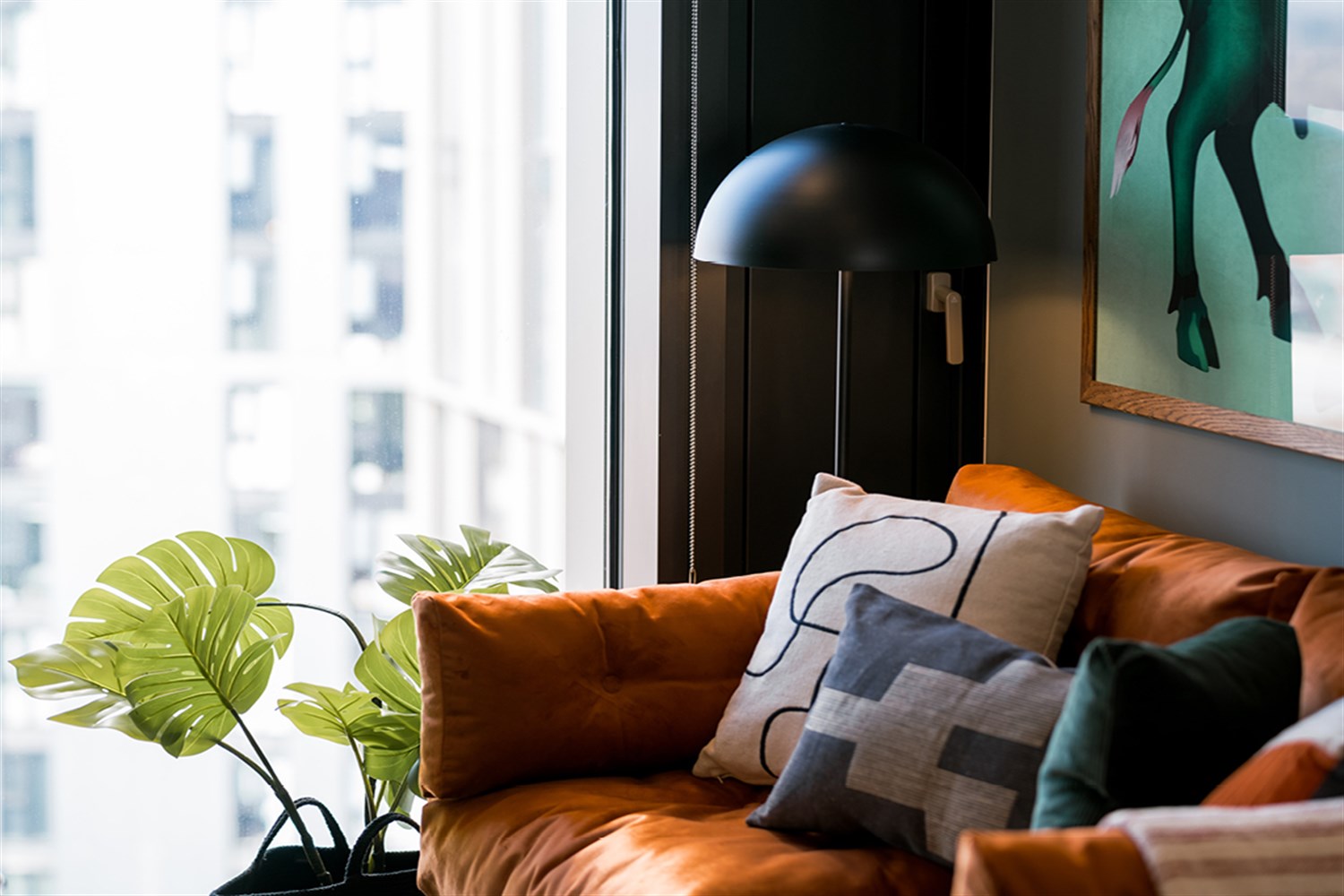 Close styling detail of cushions, lamp and planting beside a window