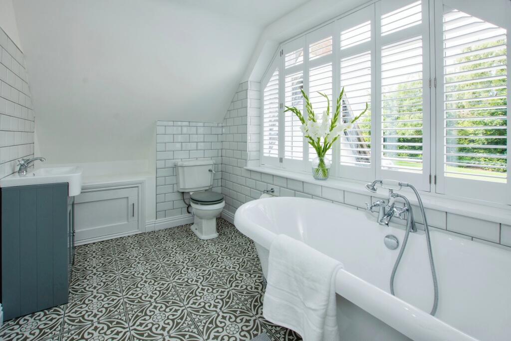 Bathroom with vanity unit, roll-top bath and patterned encaustic floor tiles