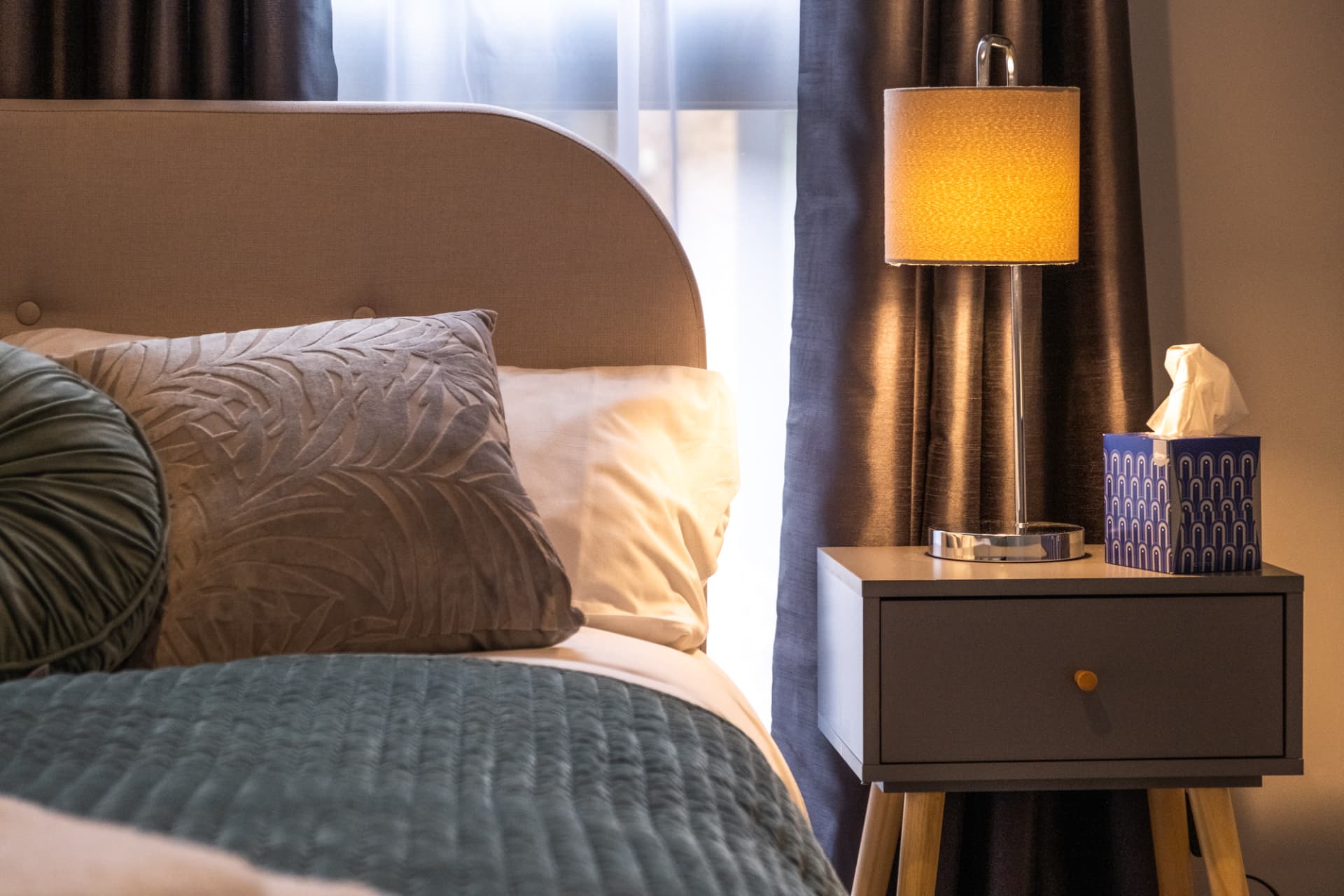 Bedside detail with lit lamp, layered cushions and guest touches