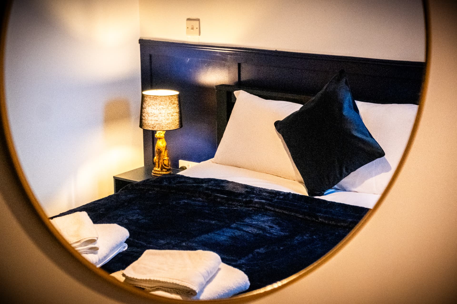 Styling detail reflected in a brass mirror with bedside lighting