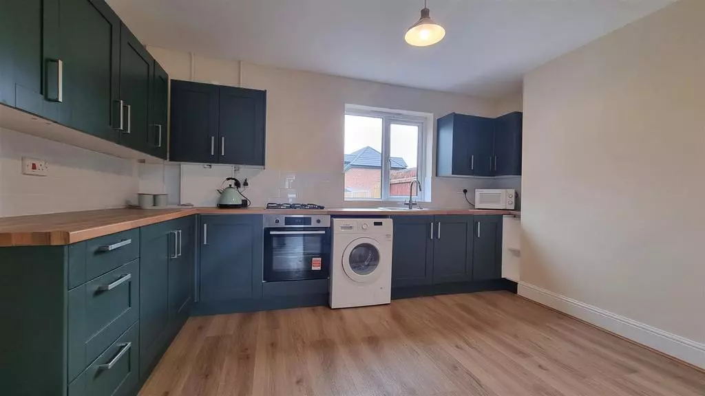 New fitted kitchen with dark green shaker units, timber worktops and integrated appliances
