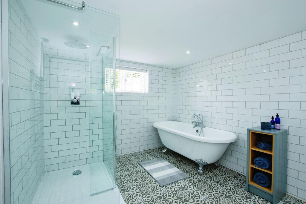 Bathroom with walk-in glass shower, freestanding bath and patterned tiled floor