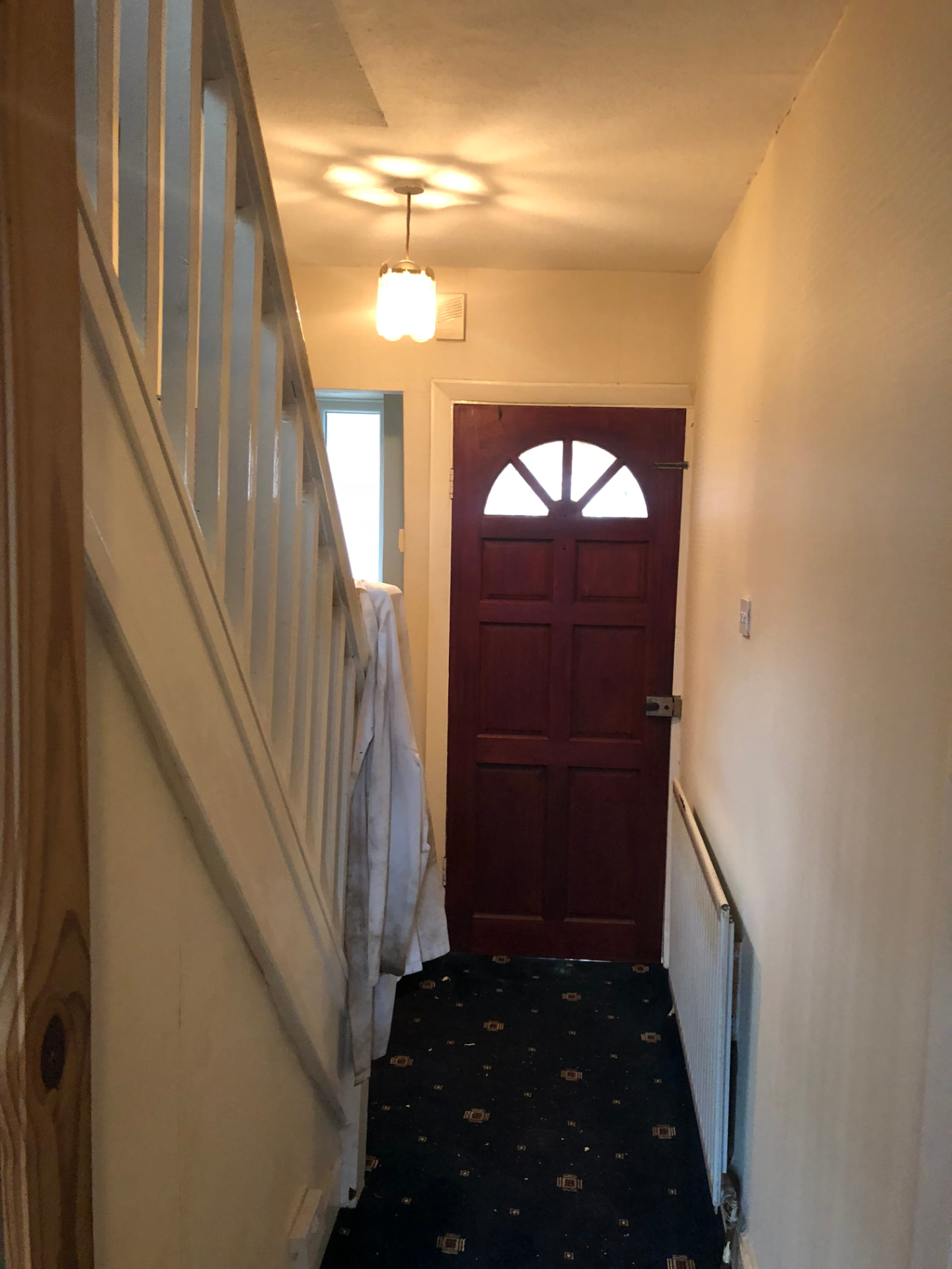 Staircase and hallway before works with dated front door, carpet and decoration