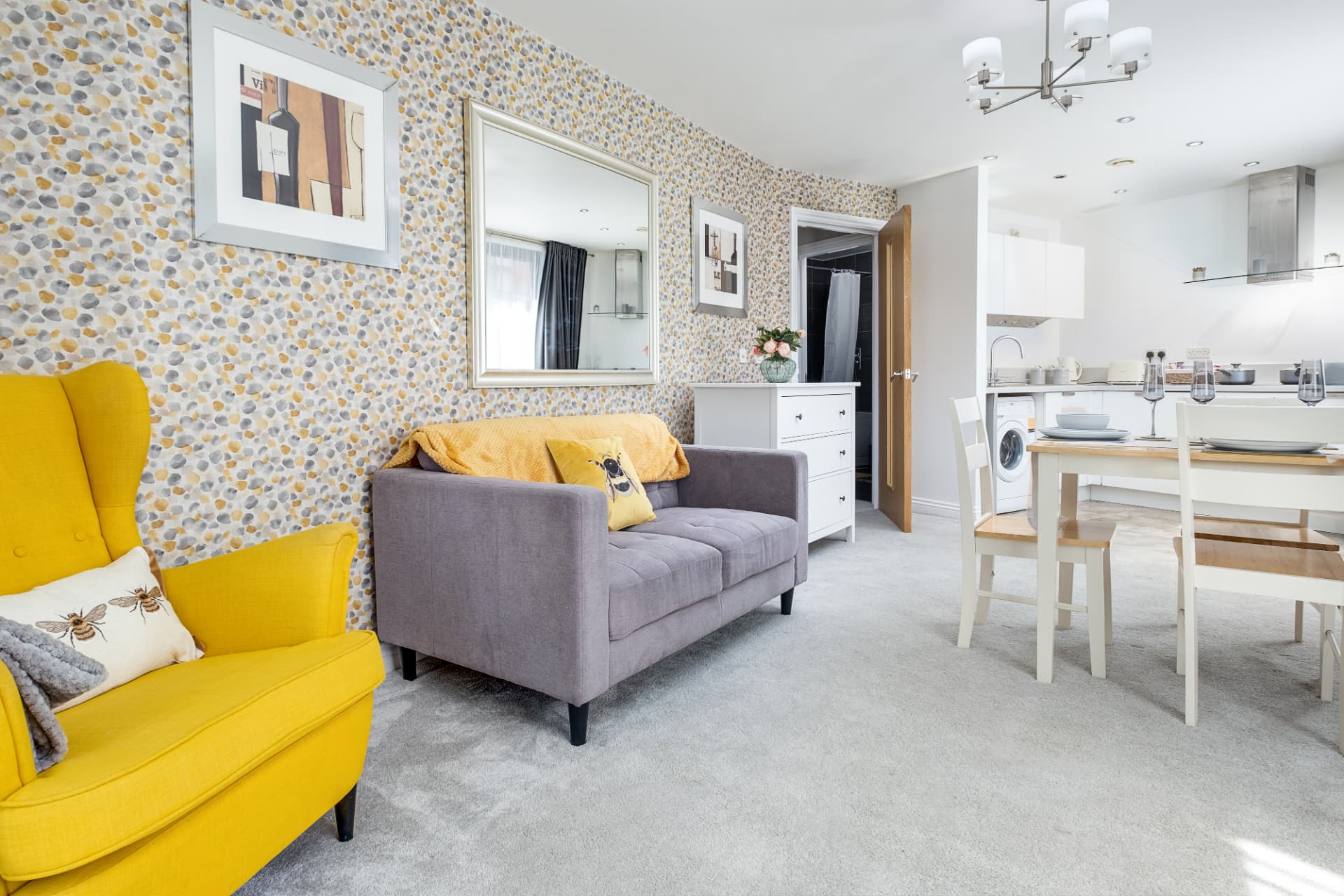 Open-plan lounge and dining area with patterned feature wall leading to a white kitchen