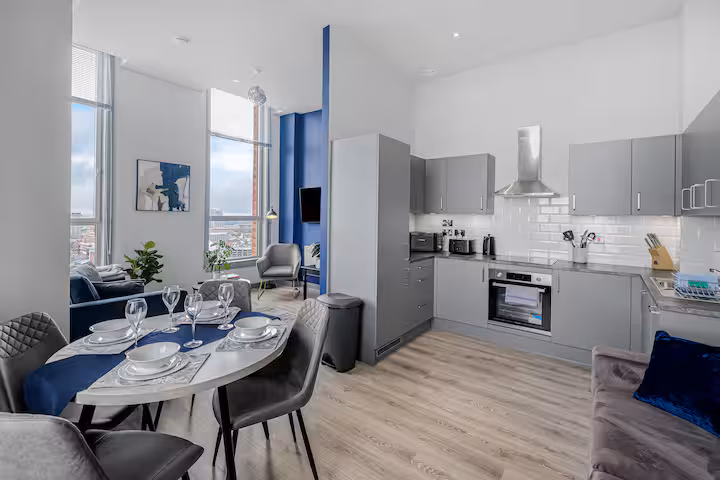 Fully equipped grey kitchen with integrated oven, extractor and adjacent dining setting