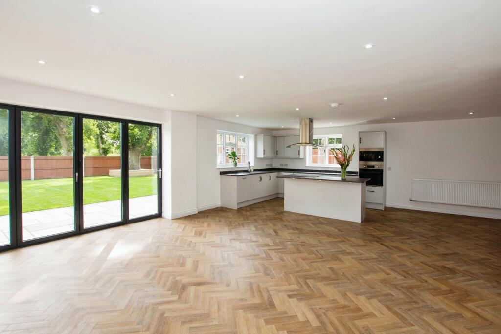 Open-plan kitchen with island, bi-fold doors and herringbone flooring