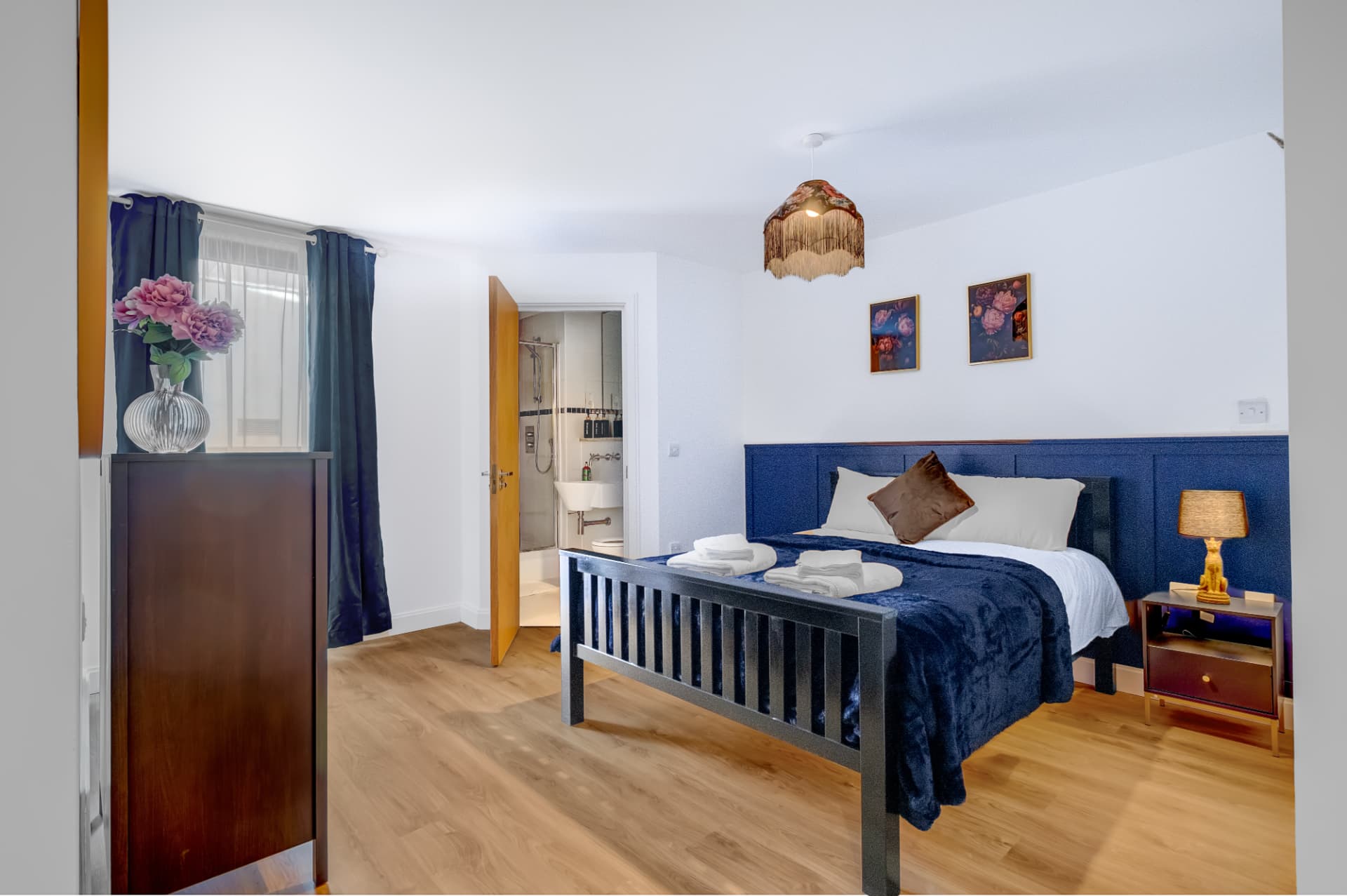 Principal bedroom with navy panelled headboard and hotel-standard linen