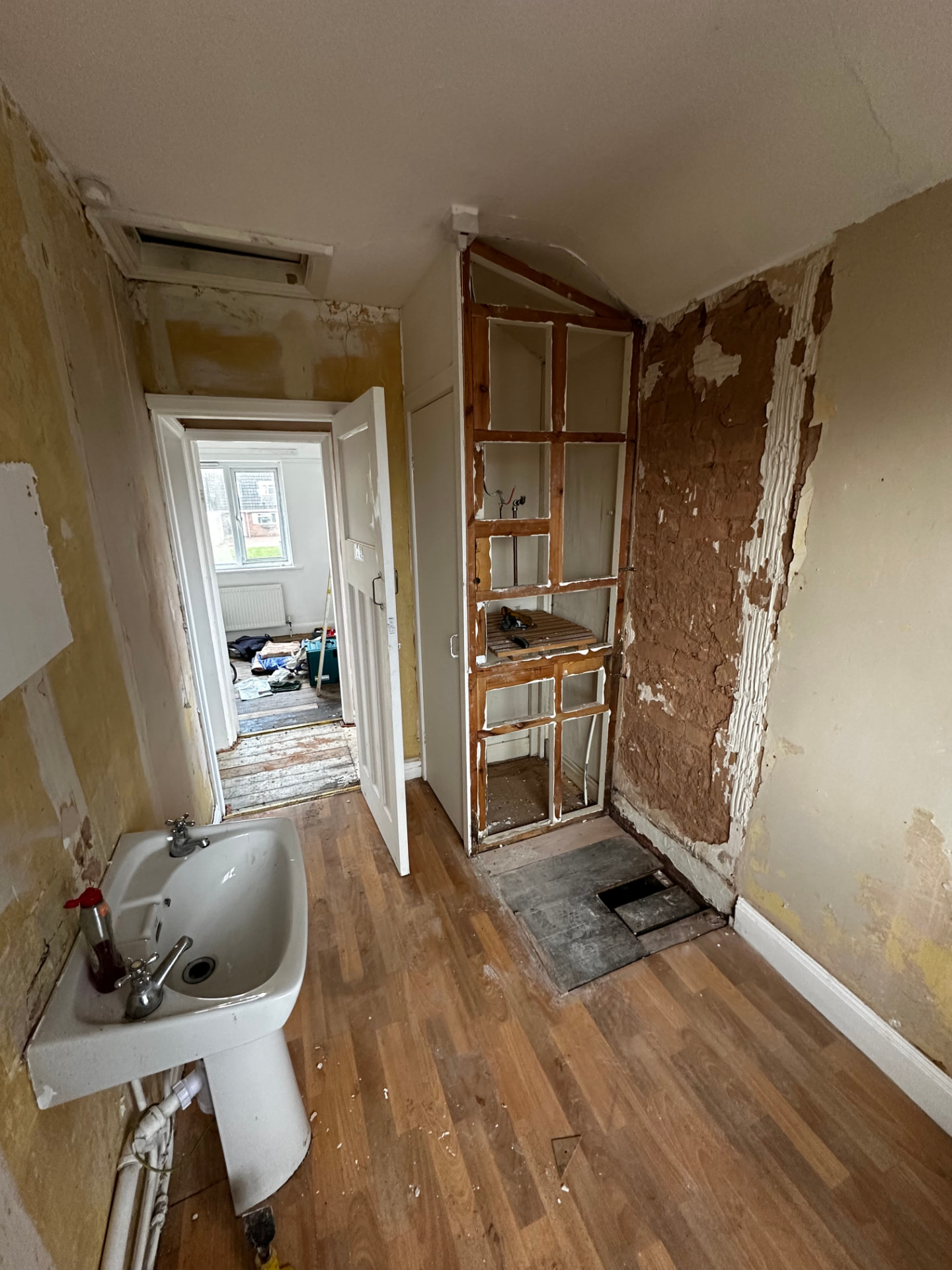 Bathroom stripped back to studwork with old basin and damaged plaster before refurbishment