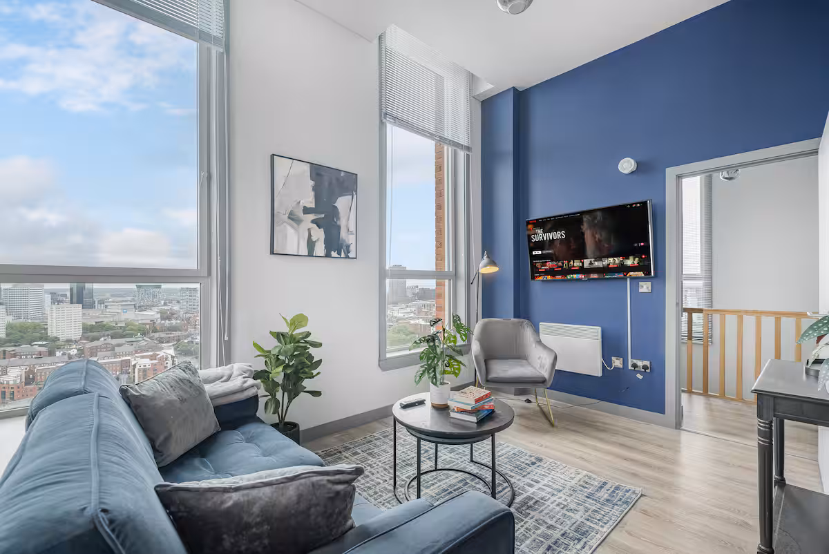 Double-height lounge with blue velvet sofa, cobalt feature wall and panoramic city views