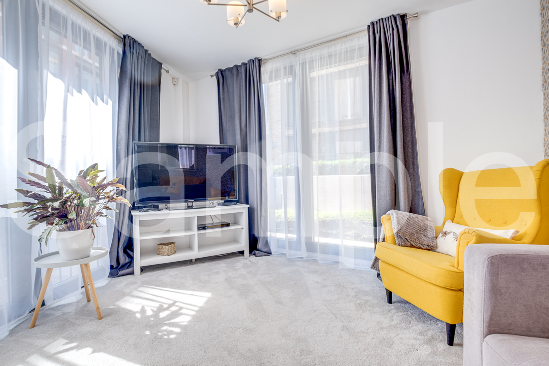 Bright lounge with mustard armchair, media unit and full-height curtains