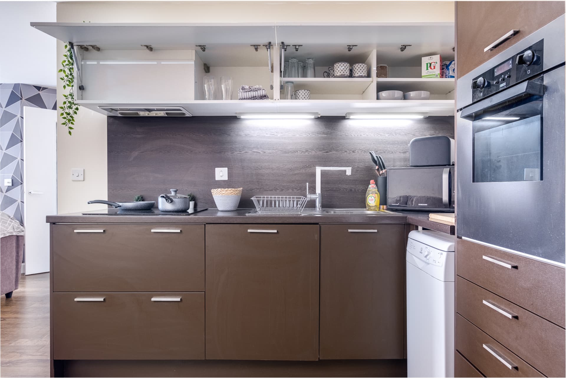 Compact fitted kitchen with dark timber units and integrated appliances