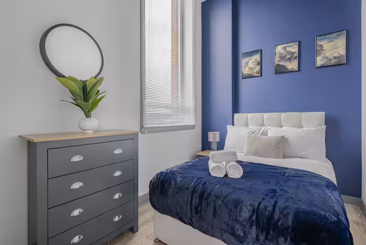 Bedroom with cobalt feature wall, white upholstered headboard and hotel-standard linen