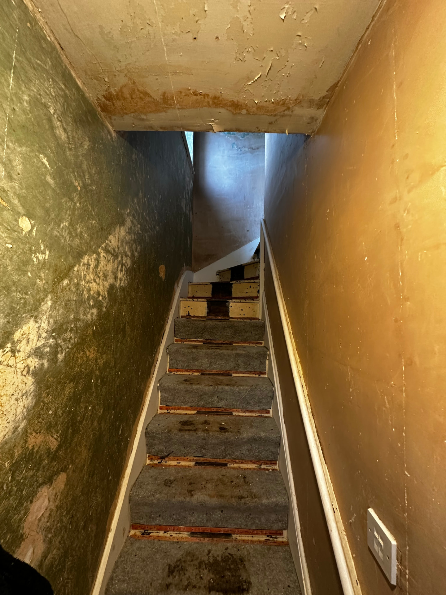 Original staircase with worn carpet and stained plasterwork before refurbishment