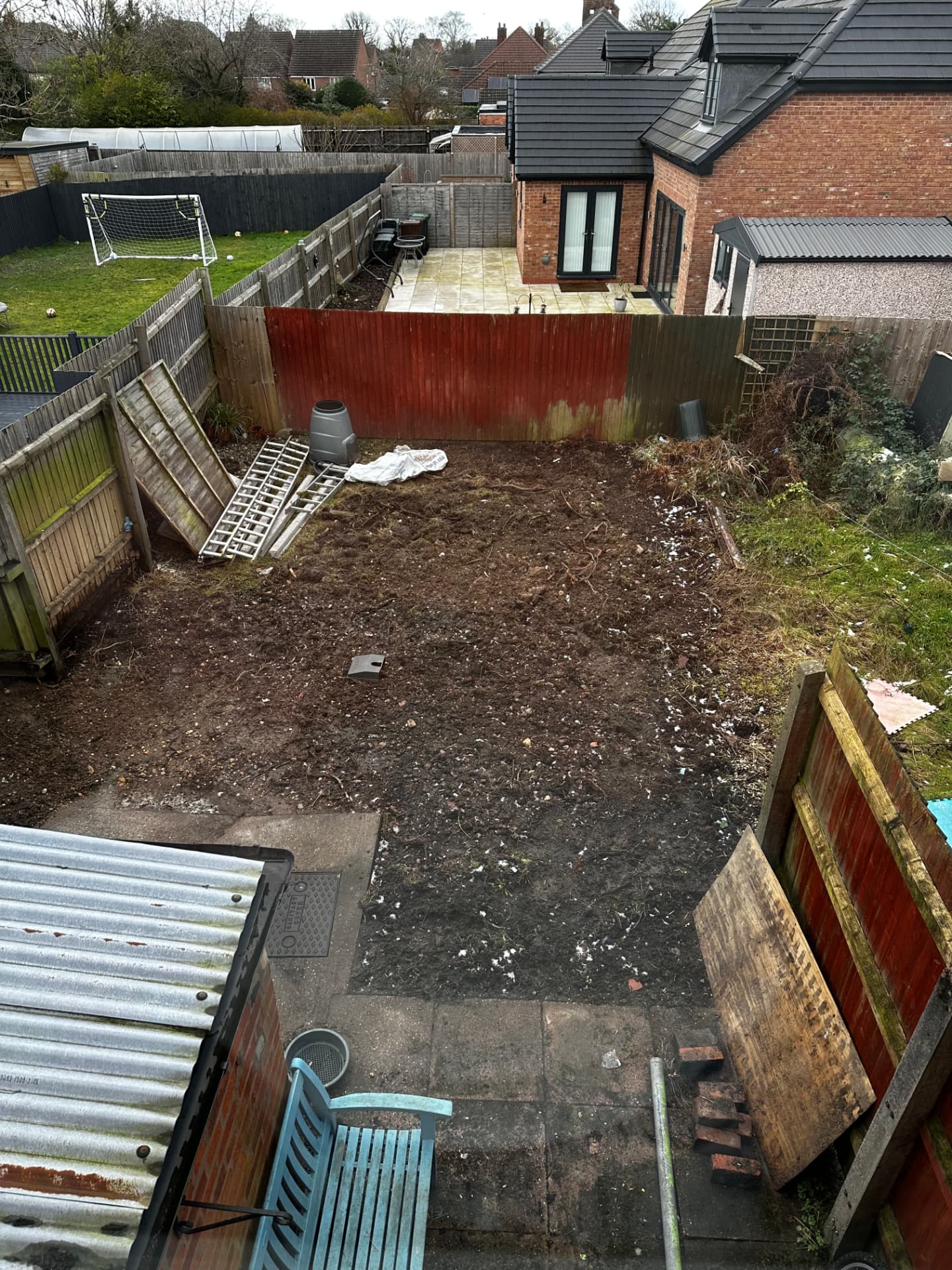 Rear garden cleared to bare soil with collapsed fence panels before landscaping